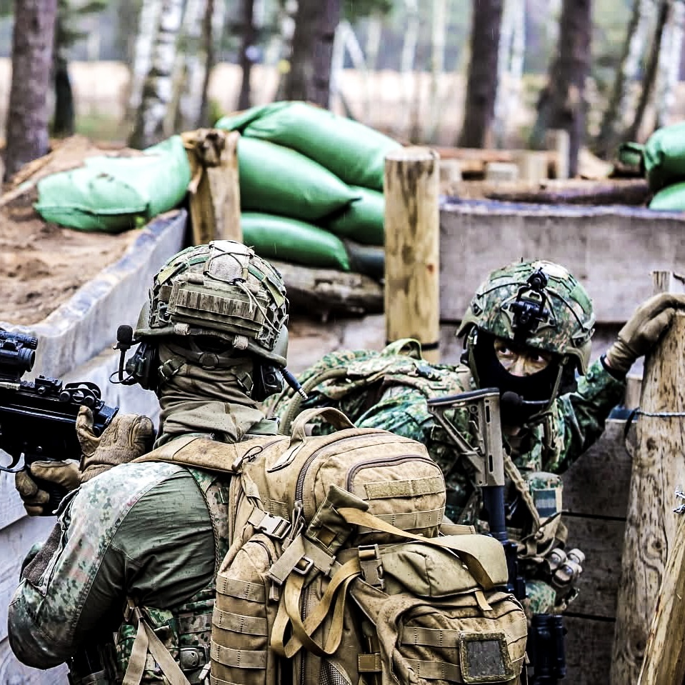 Two armed soliders in trenches waiting.