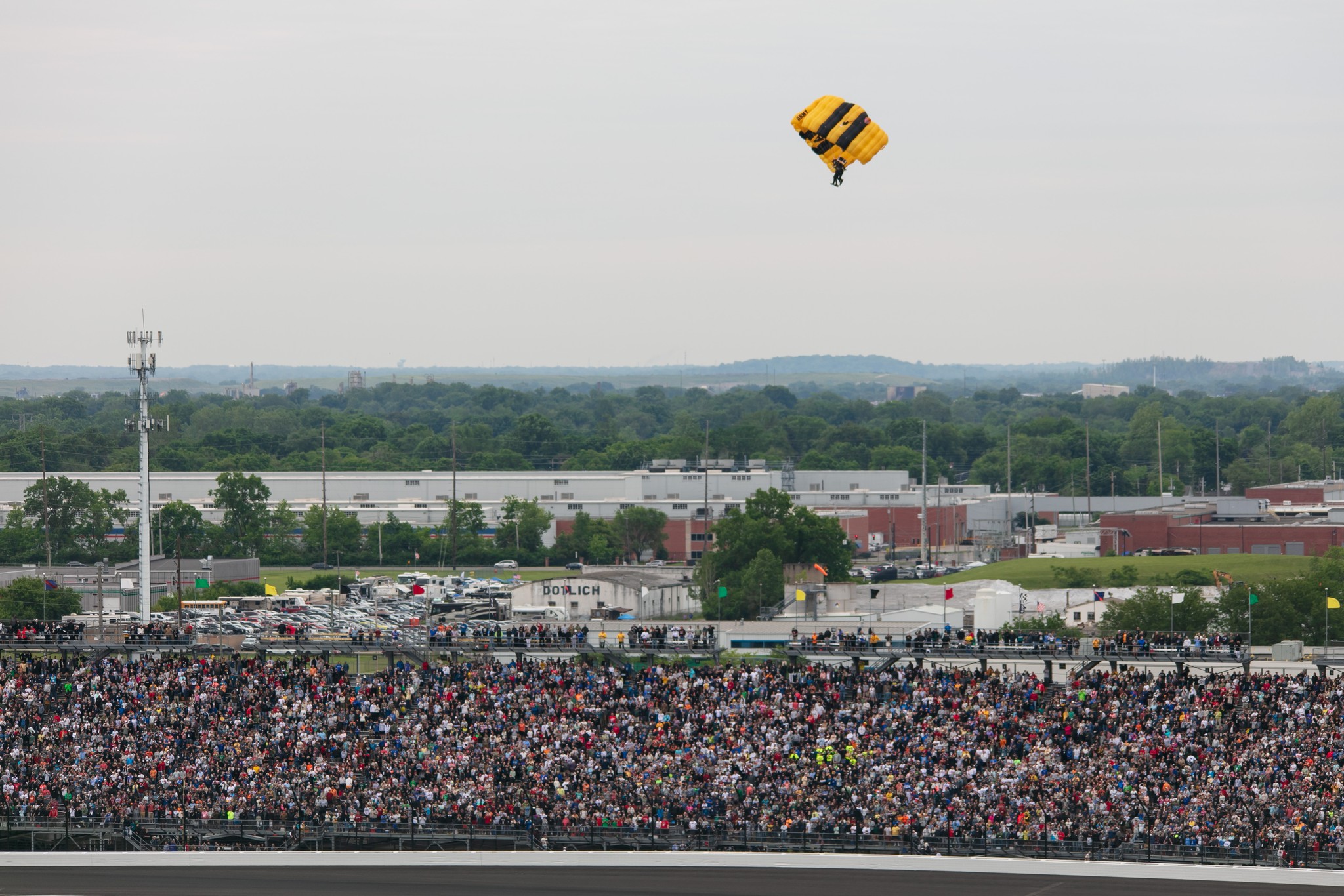 Wide view of skydiver over a large crowd of people.